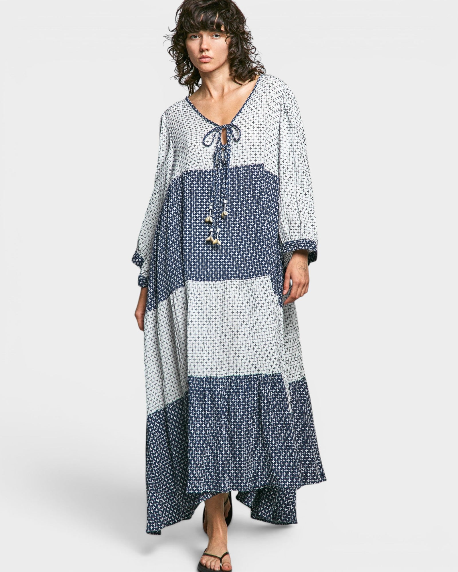 Woman wearing a long, patterned dress with blue and white color scheme on a white background