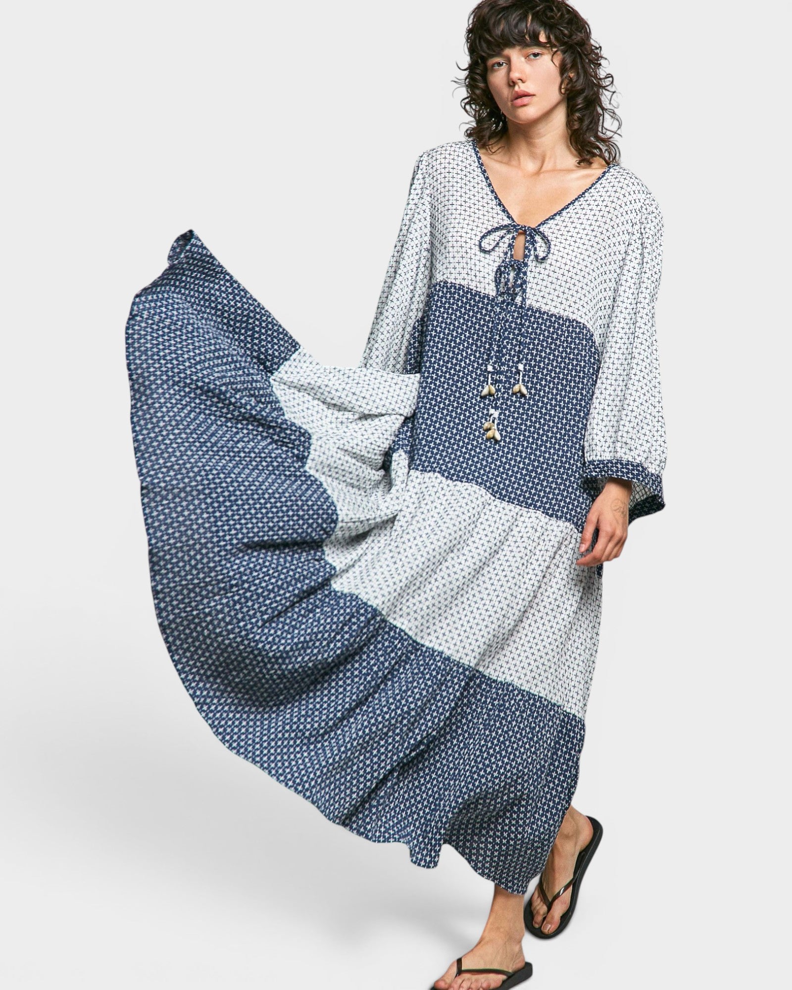 Woman wearing a long, patterned dress with a white background