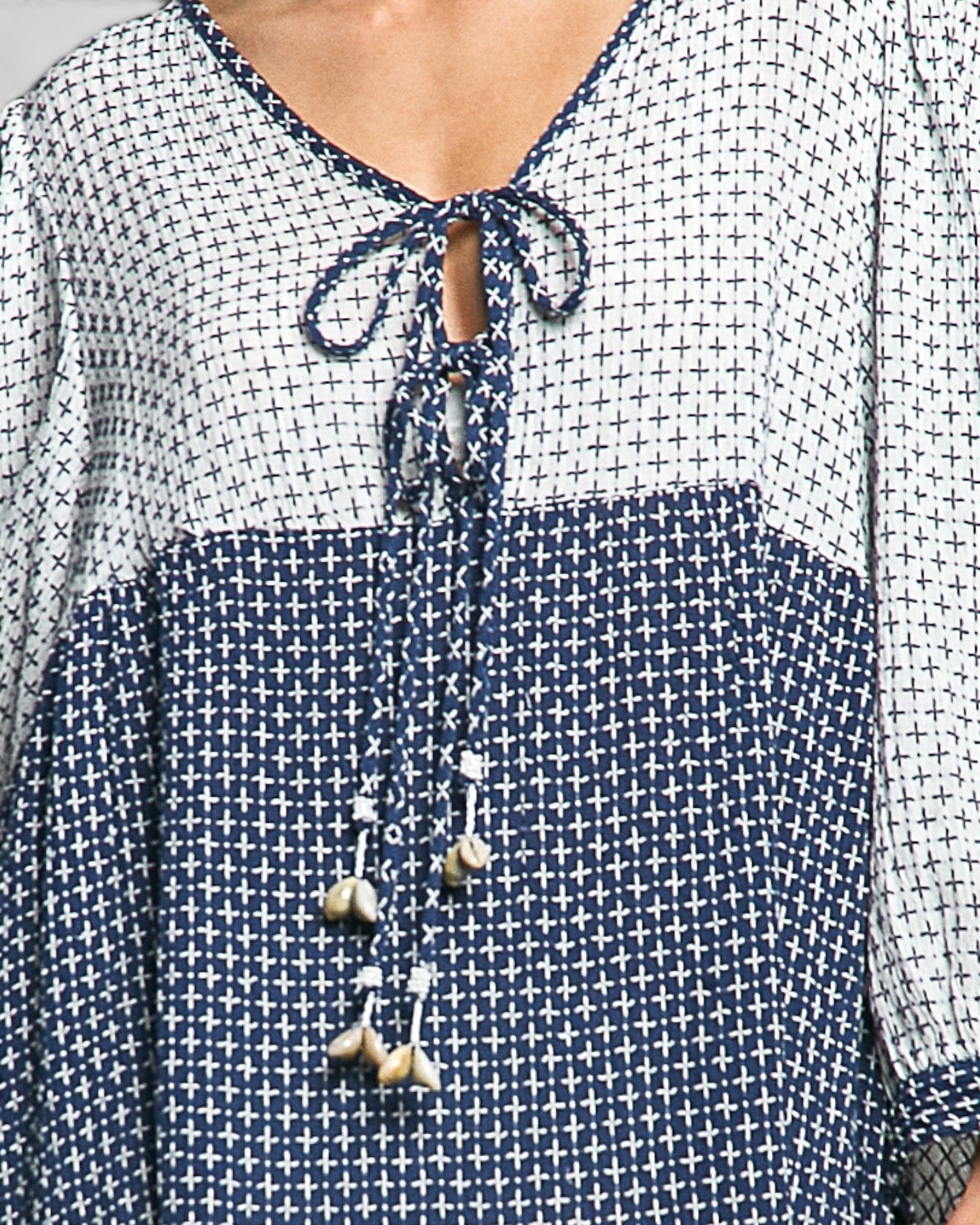 Close-up of a blue and white patterned blouse with a tie detail.