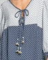 Close-up of a blue and white patterned blouse with a tie detail.