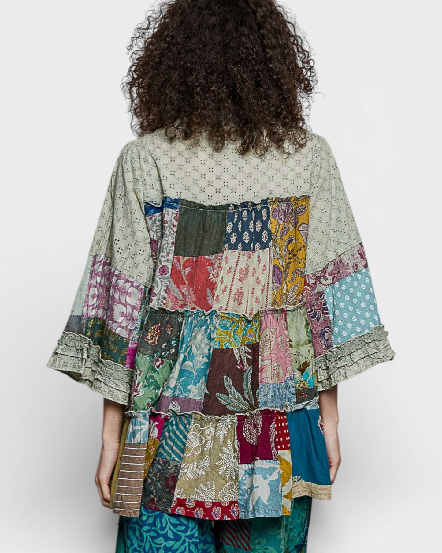 Person wearing a colorful patchwork kimono-style garment on a white background