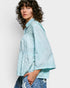 Person wearing a light blue patterned shirt against a white background