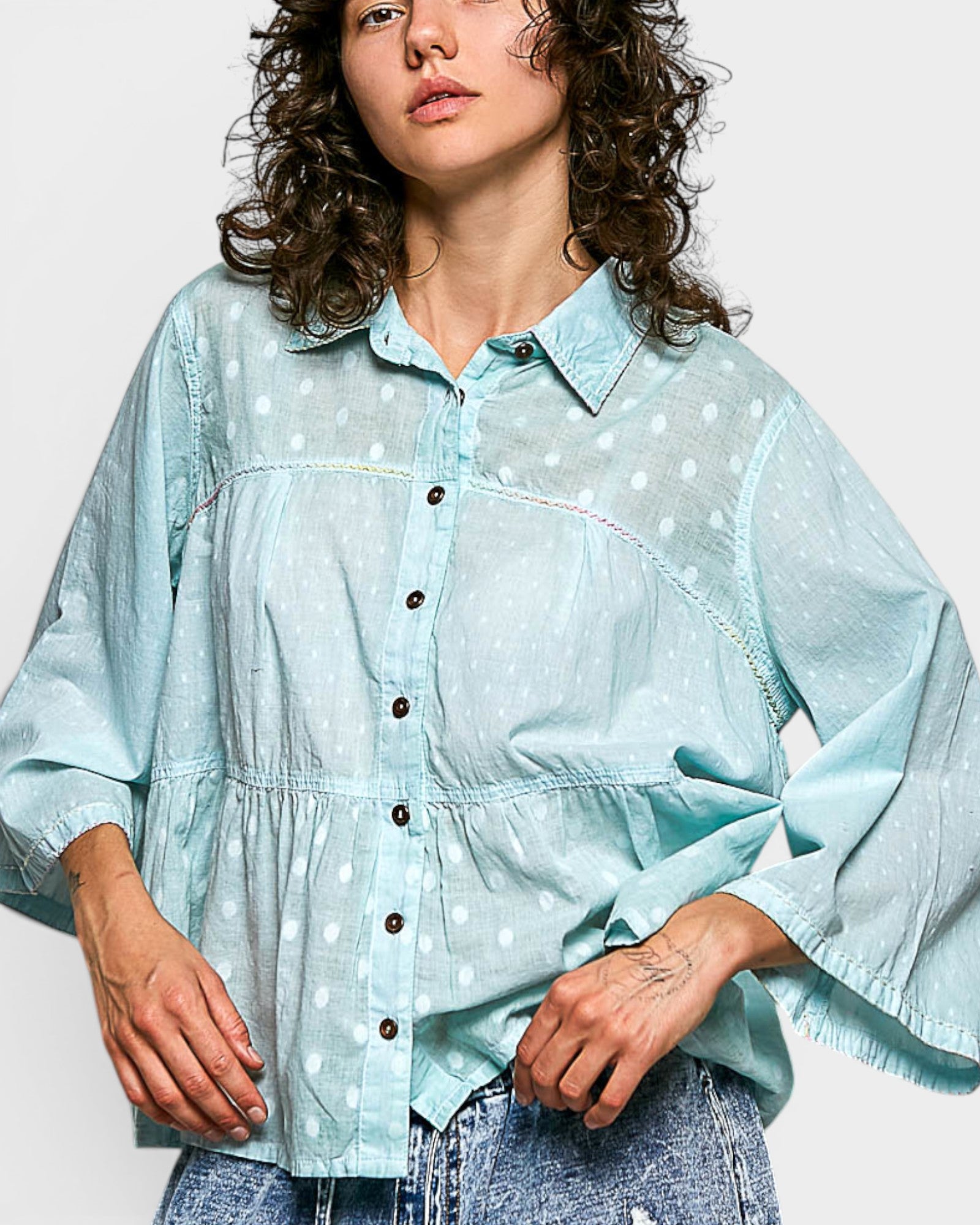 Woman wearing a light blue polka dot shirt against a white background