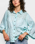 Woman wearing a light blue polka dot shirt against a white background