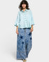 Person wearing a light blue shirt and denim pants with star patterns on a white background