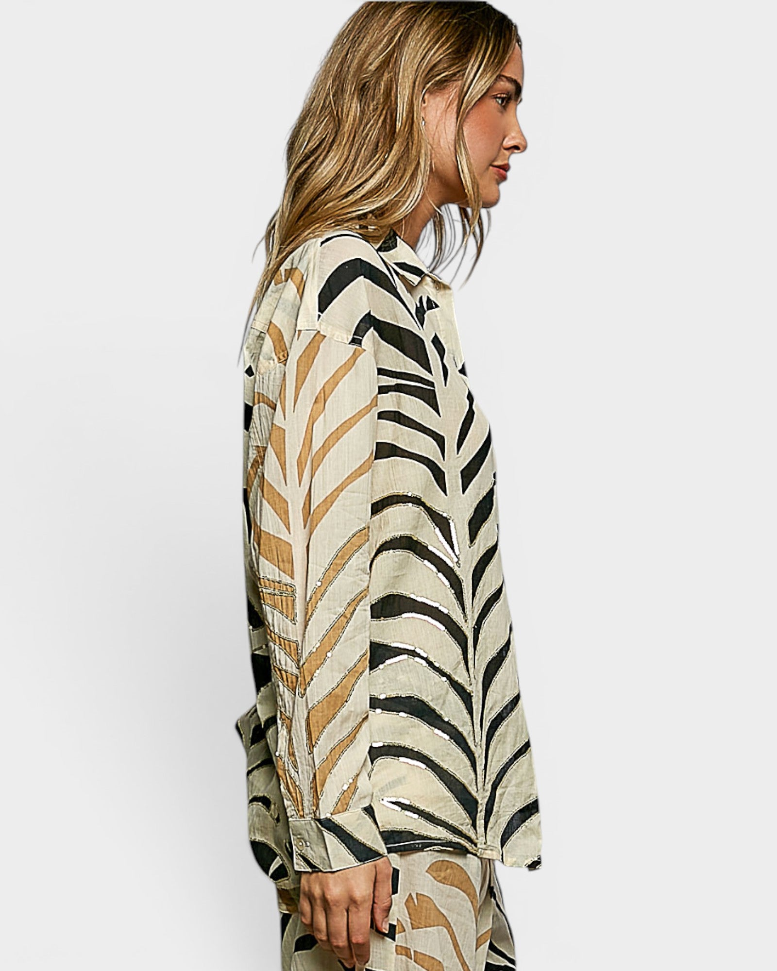Woman wearing a patterned top with abstract design on a plain background