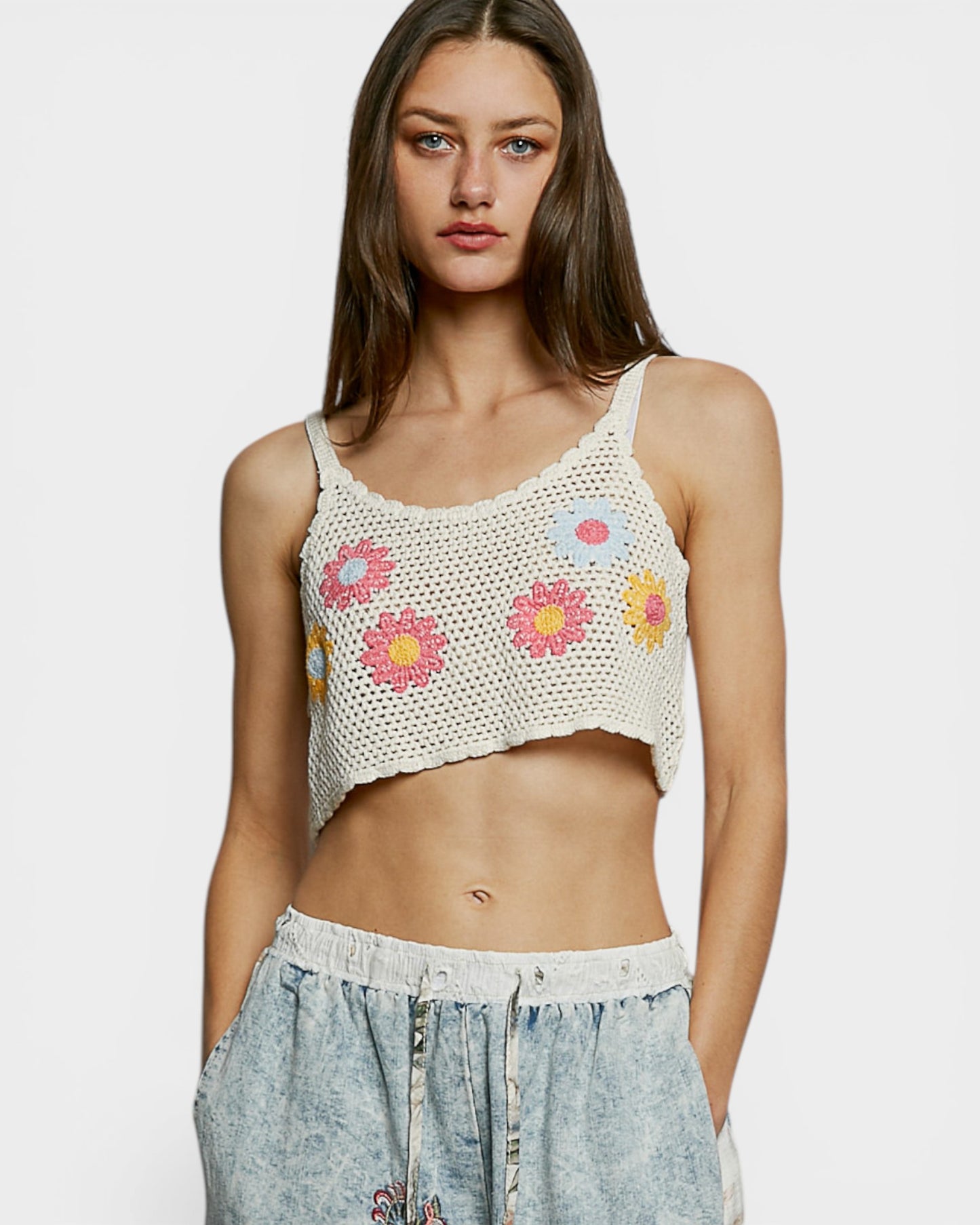 Woman wearing a crochet tank top with floral patterns on a white background