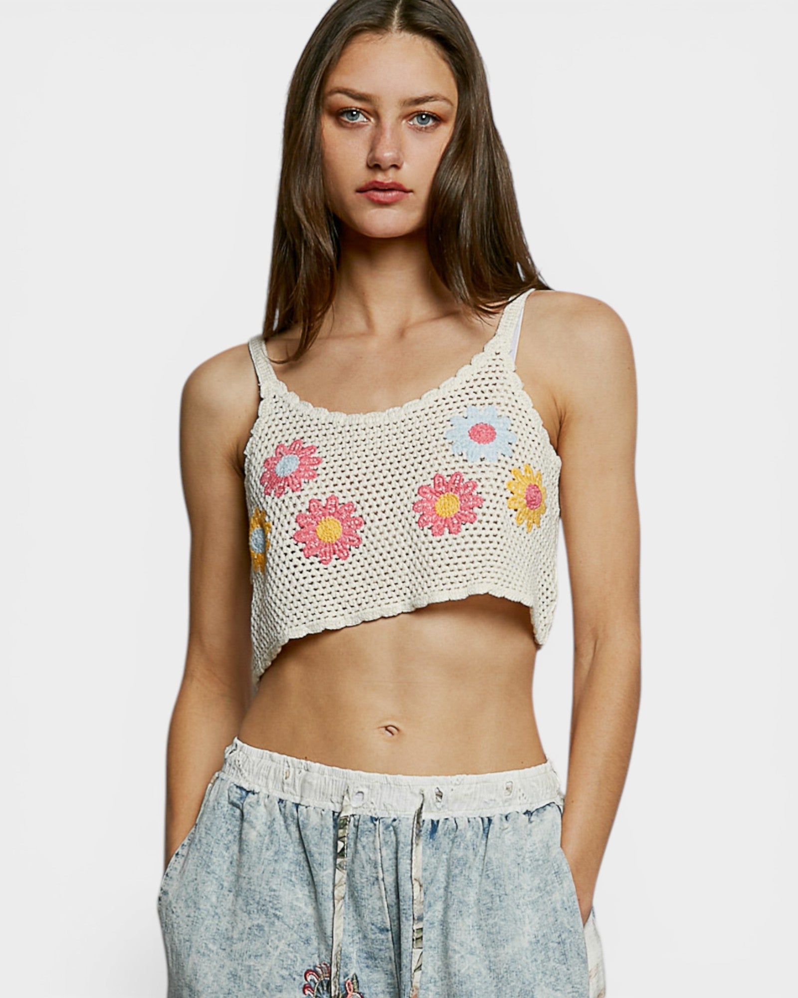Woman wearing a crochet tank top with floral patterns on a white background