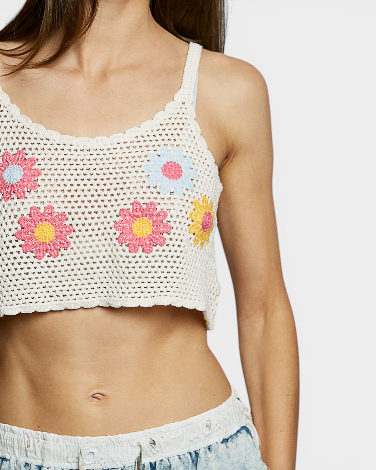 White crochet top with floral designs on a plain background