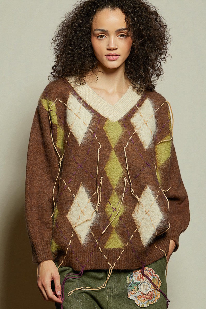 Woman wearing a brown argyle sweater with a neutral background