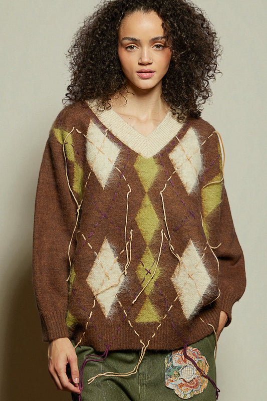 Woman wearing a brown argyle sweater with a neutral background