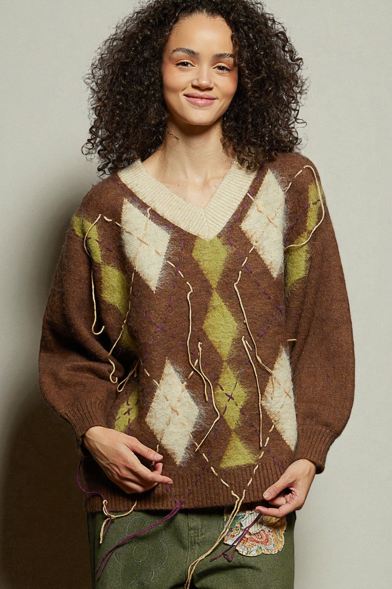 Woman wearing a brown sweater with geometric pattern against a neutral background