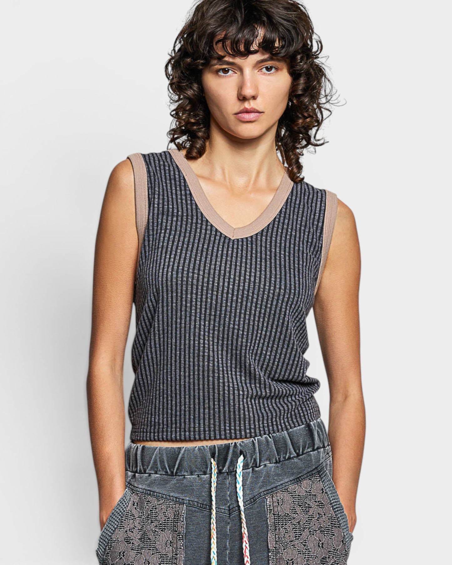 Person wearing a sleeveless knitted top with sheer mesh panels on a plain background