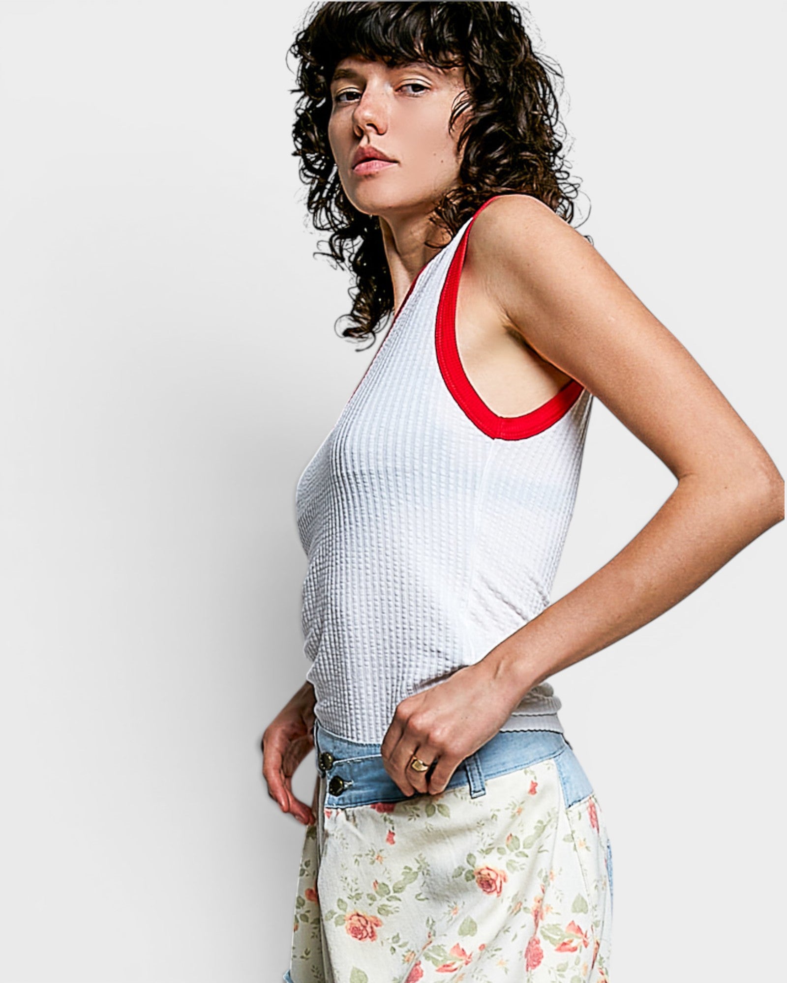 Woman wearing a white tank top with red trim against a plain background