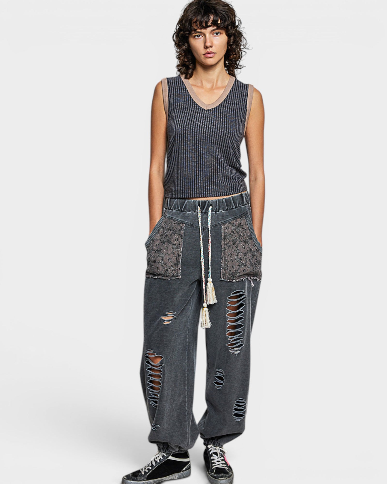 Person wearing a sleeveless top and distressed jeans on a white background