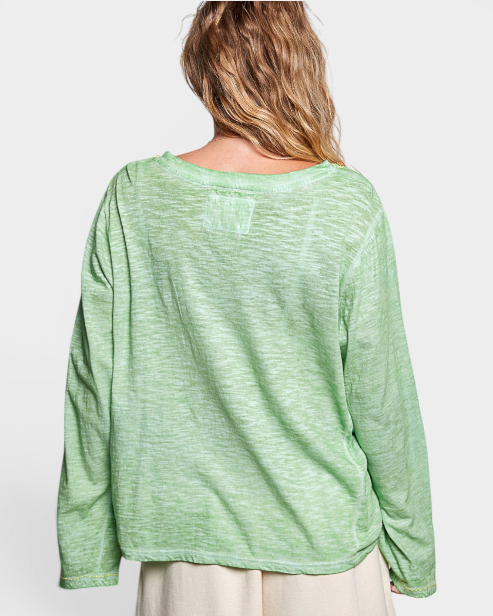 Green long-sleeve top worn by a person on a white background