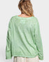 Green long-sleeve top worn by a person on a white background