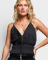 Woman wearing a black sleeveless top with a deep neckline on a plain background