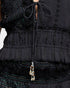 Close-up of a black textured top with a beaded detail on a white background