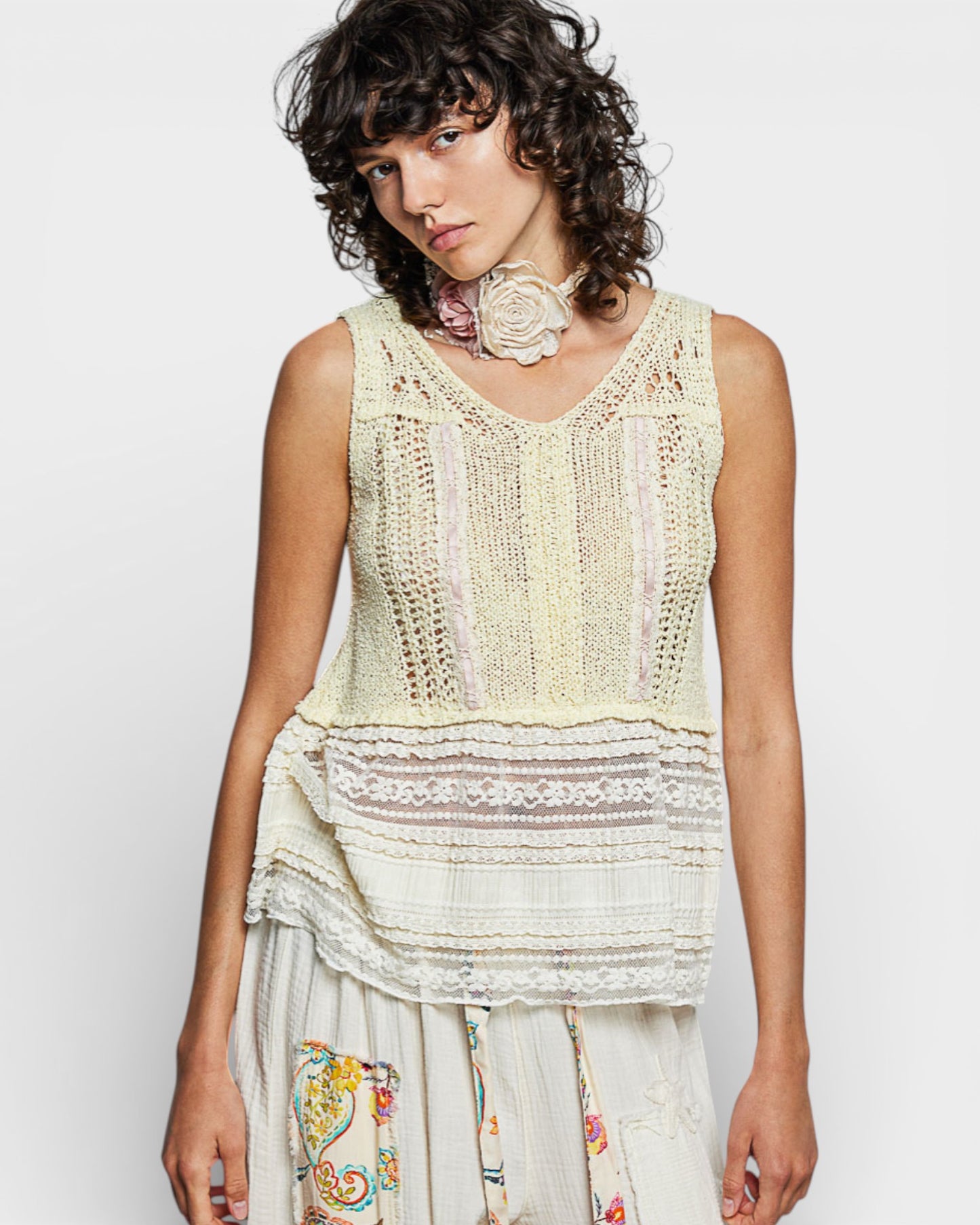 Woman wearing a light-colored crochet top with a plain background