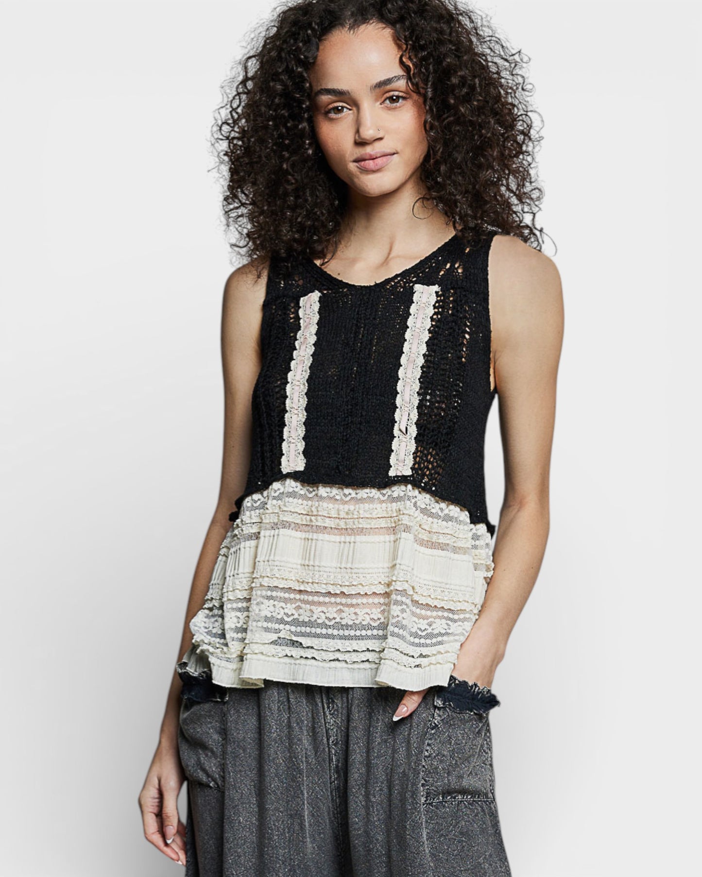 Woman wearing a black and white layered top with gray pants on a white background