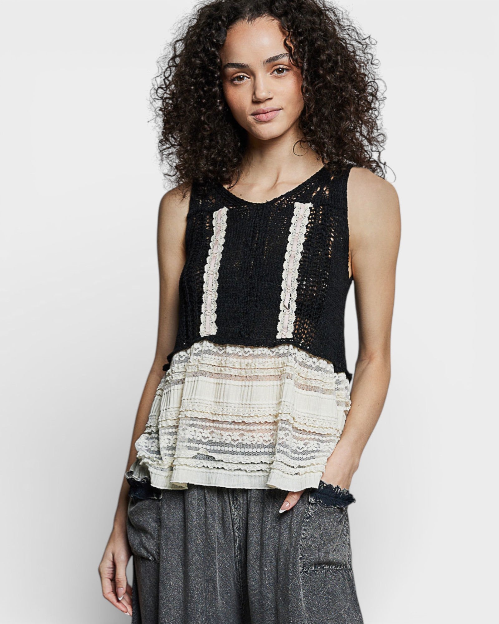 Woman wearing a black and white layered top with gray pants on a white background