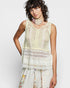 Woman wearing a light green crochet top and floral pants on a white background