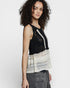Woman wearing a black and white patterned sleeveless top on a white background