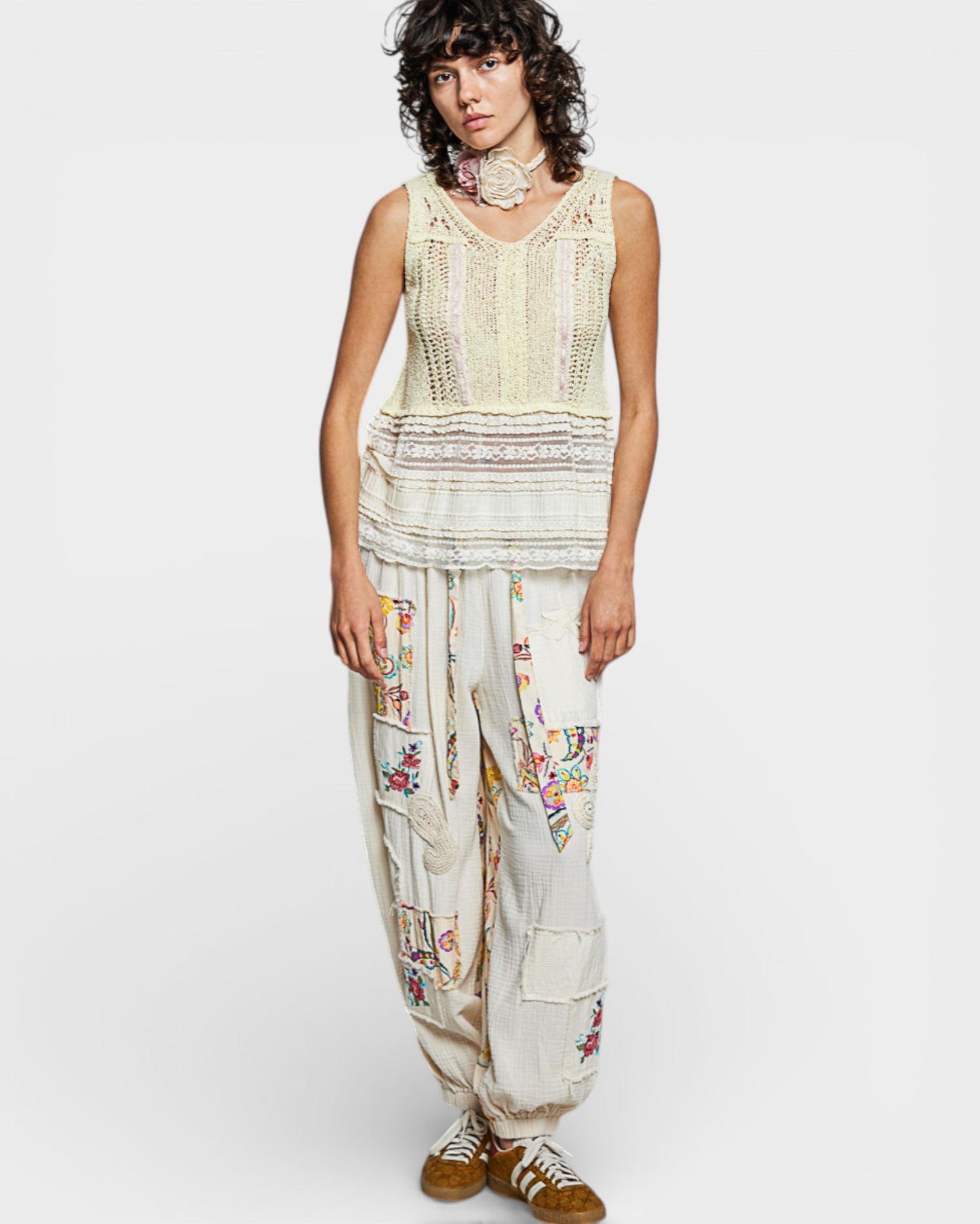 Woman wearing a sleeveless top and embroidered pants on a white background