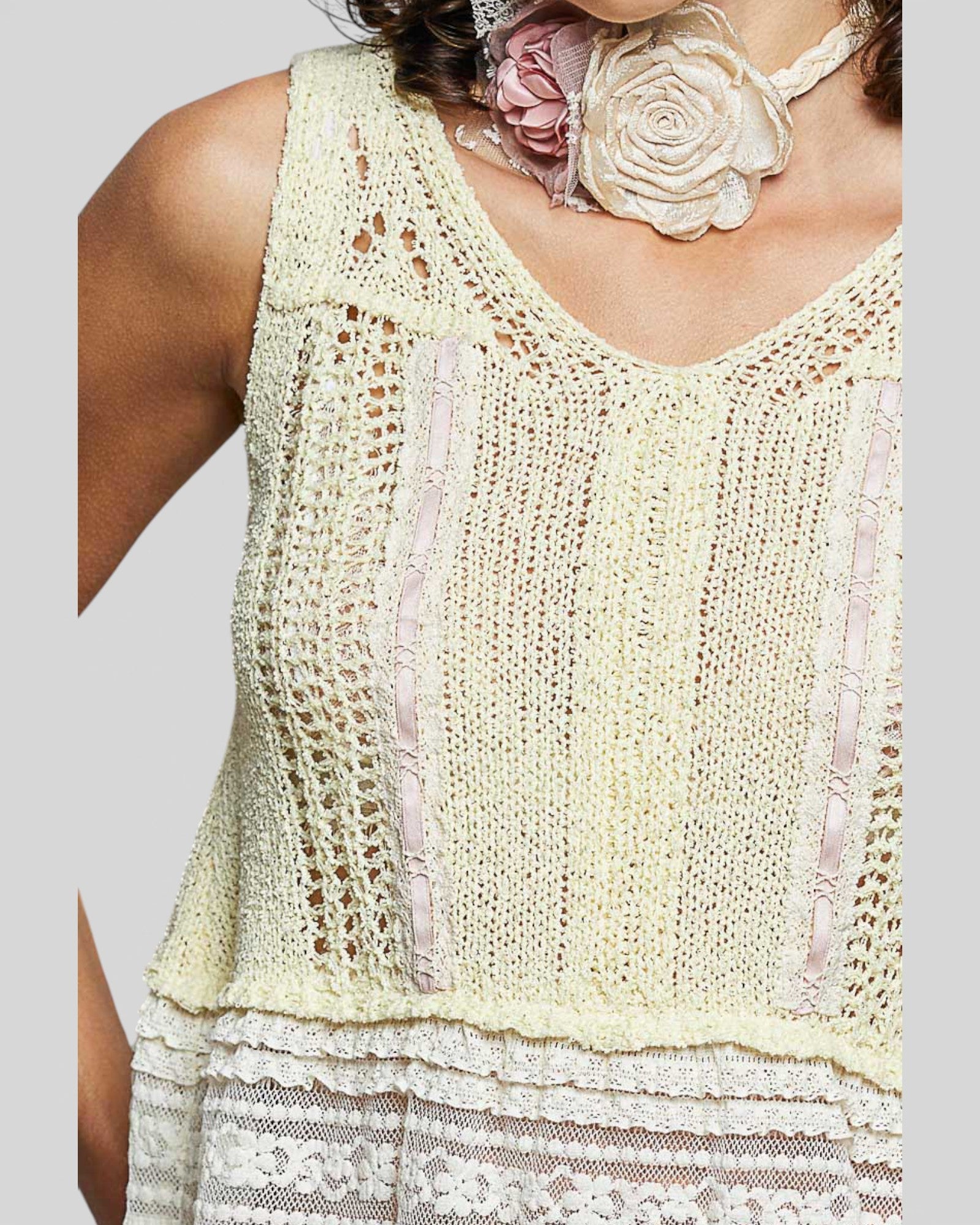 Light yellow lace top worn by a person on a plain background