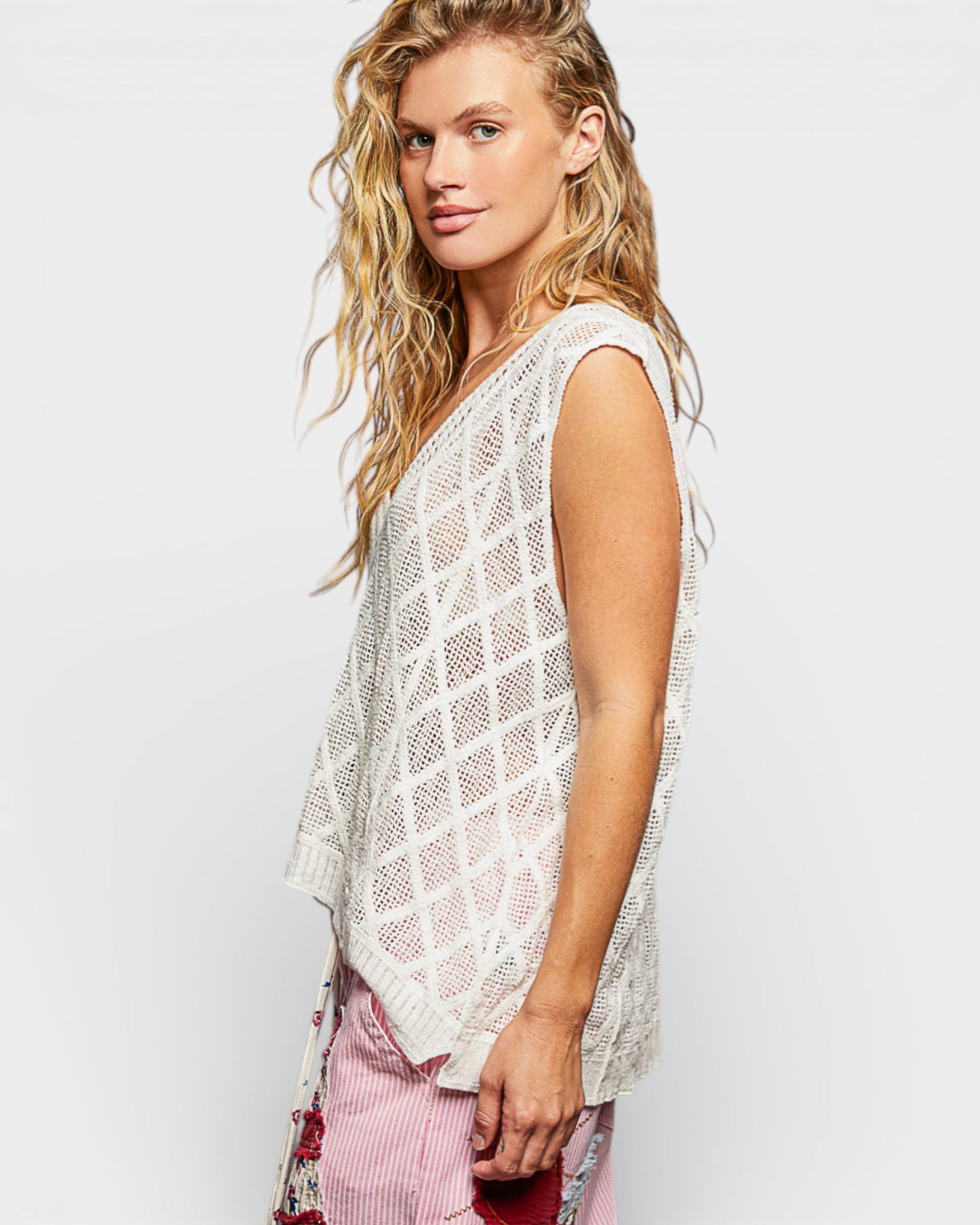 Woman wearing a white mesh top with a plain background