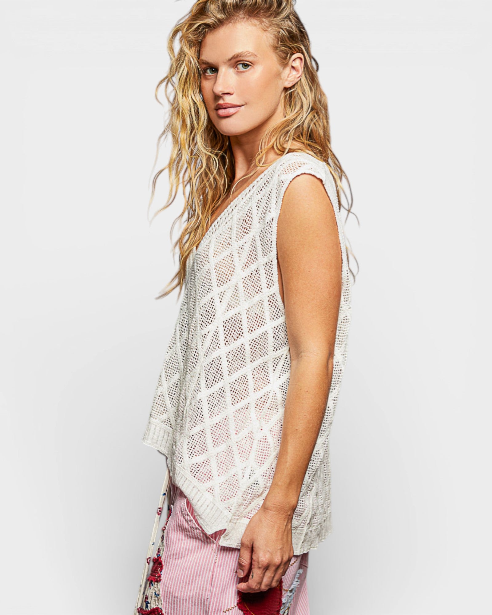 Woman wearing a white mesh top with a plain background