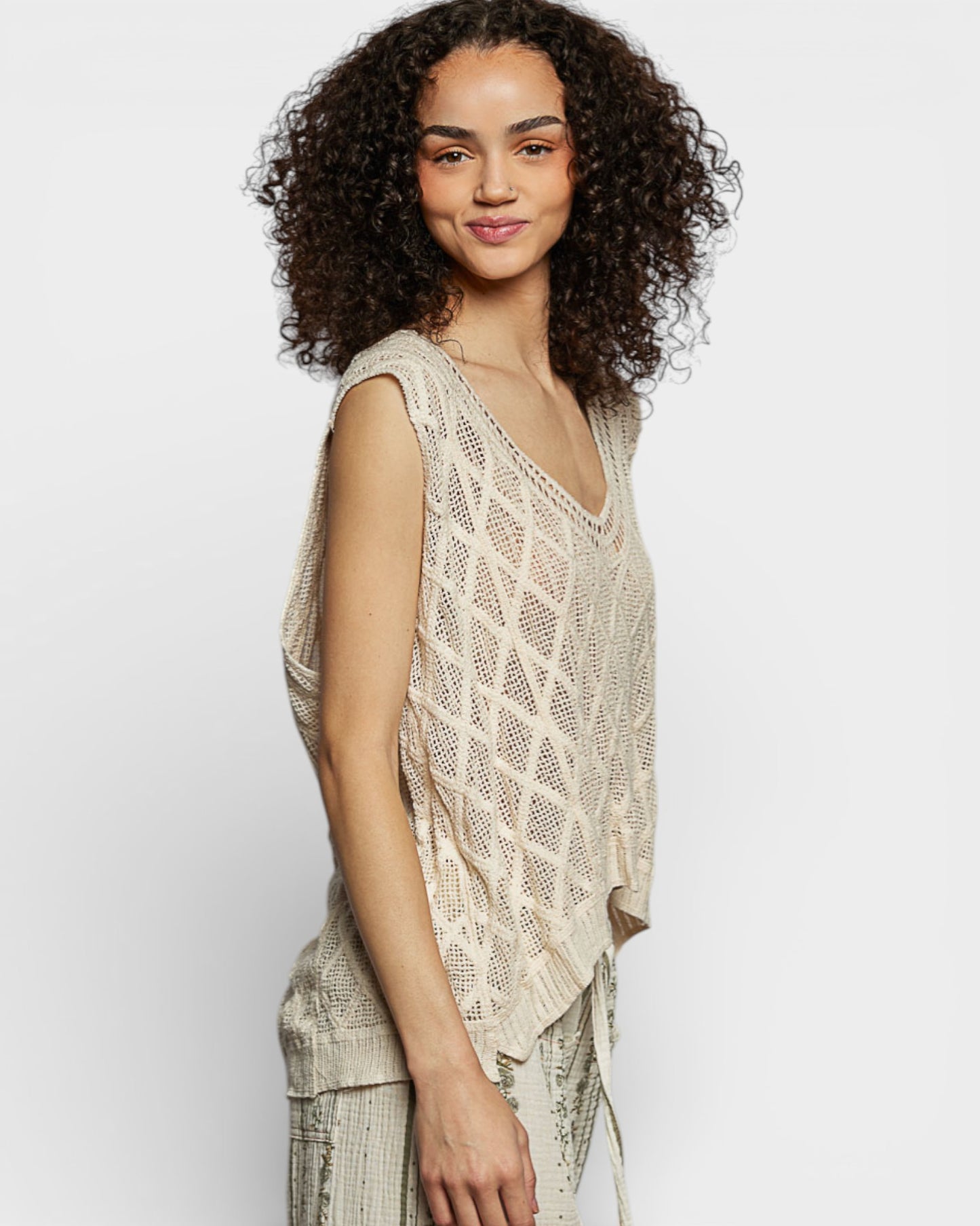 Woman wearing a beige sleeveless top with a white background