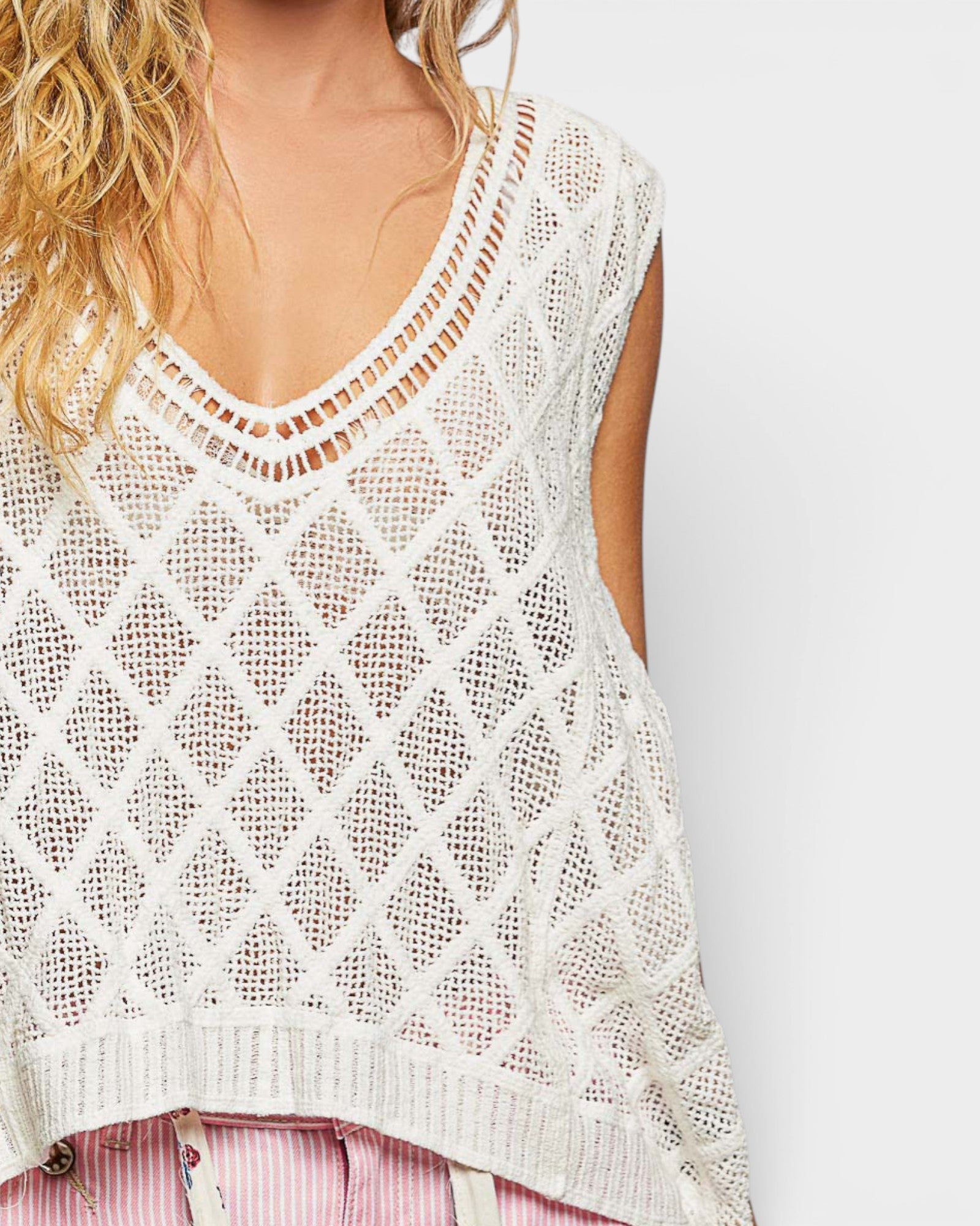 White crochet sleeveless top worn by a person on a plain background