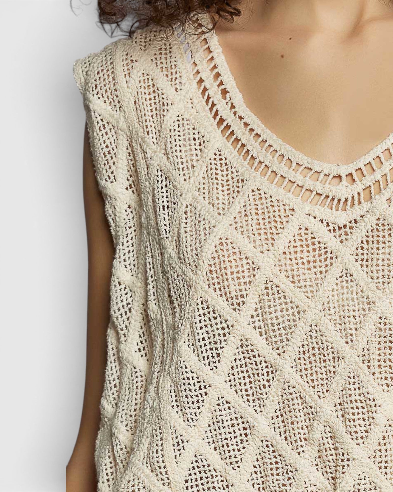 Close-up of a beige knitted sleeveless top on a plain background