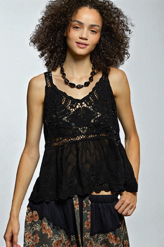 Woman wearing a black lace top with floral skirt on a plain background