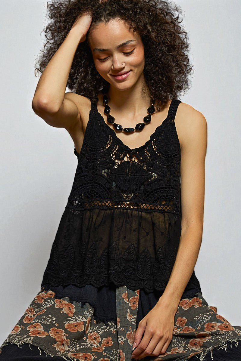 Woman wearing a black lace top and floral skirt against a plain background