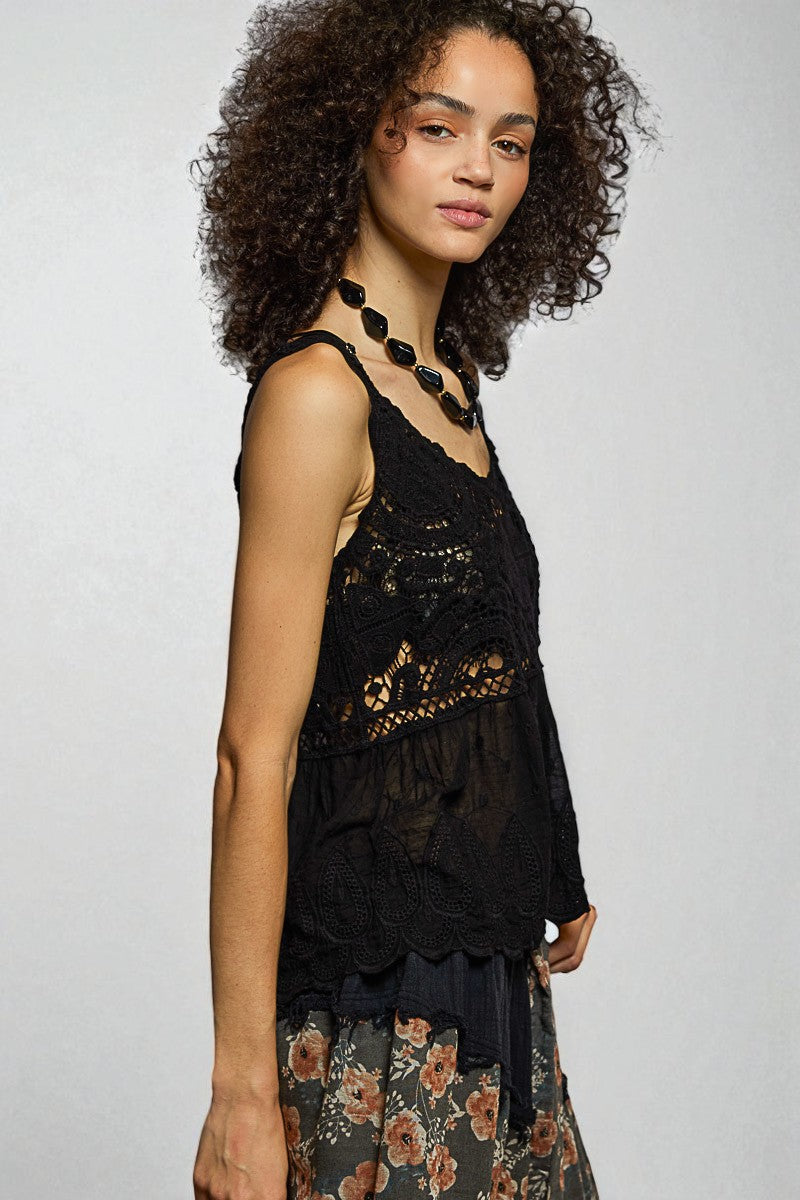 Woman wearing a black lace top with a floral skirt on a plain background