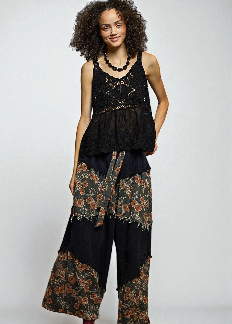 Woman wearing a black sleeveless top and floral pants on a white background