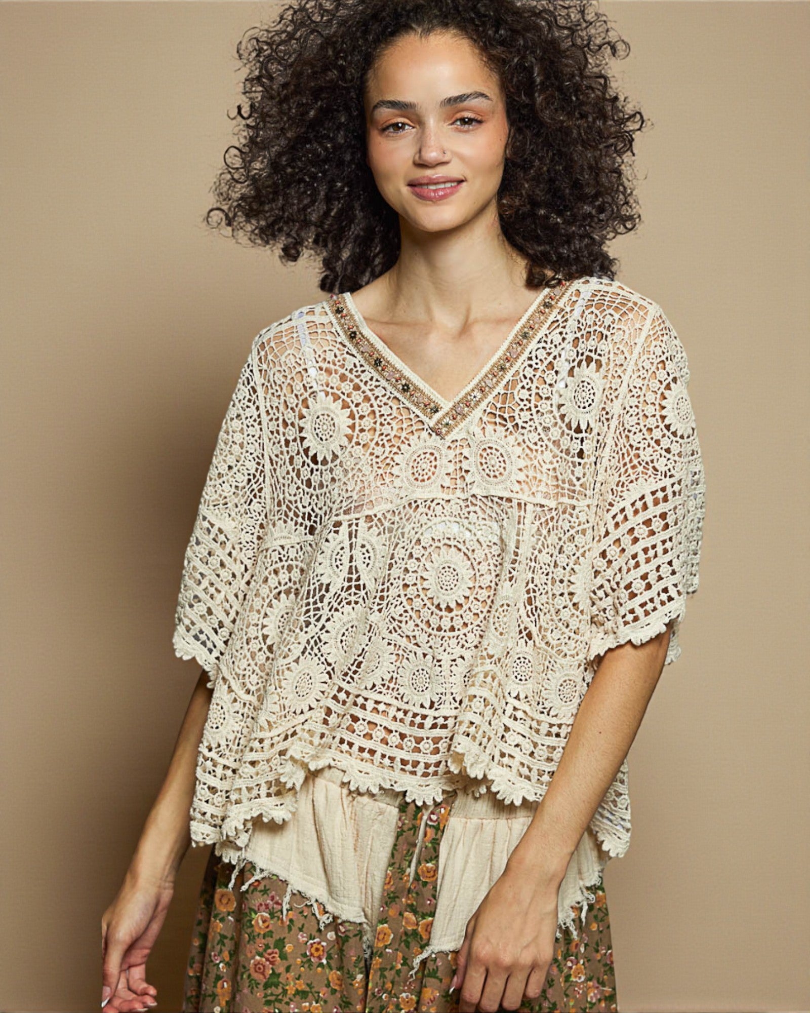 Woman wearing a beige crochet top against a beige background