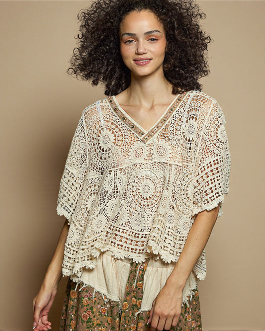 Woman wearing a beige crochet top against a beige background
