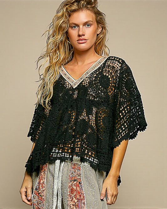 Woman wearing a black crochet top against a beige background
