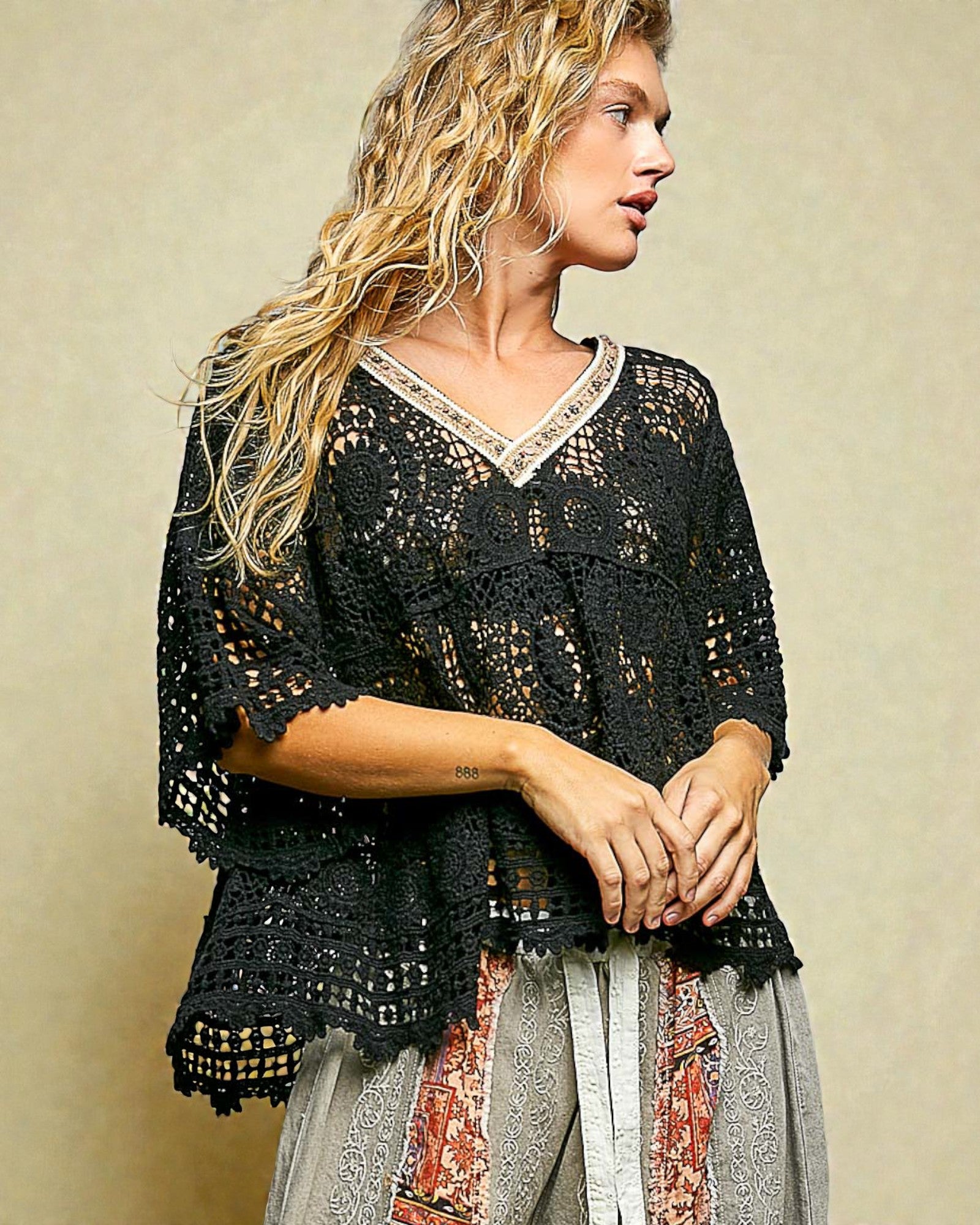 Woman wearing a black crochet top with a beige background