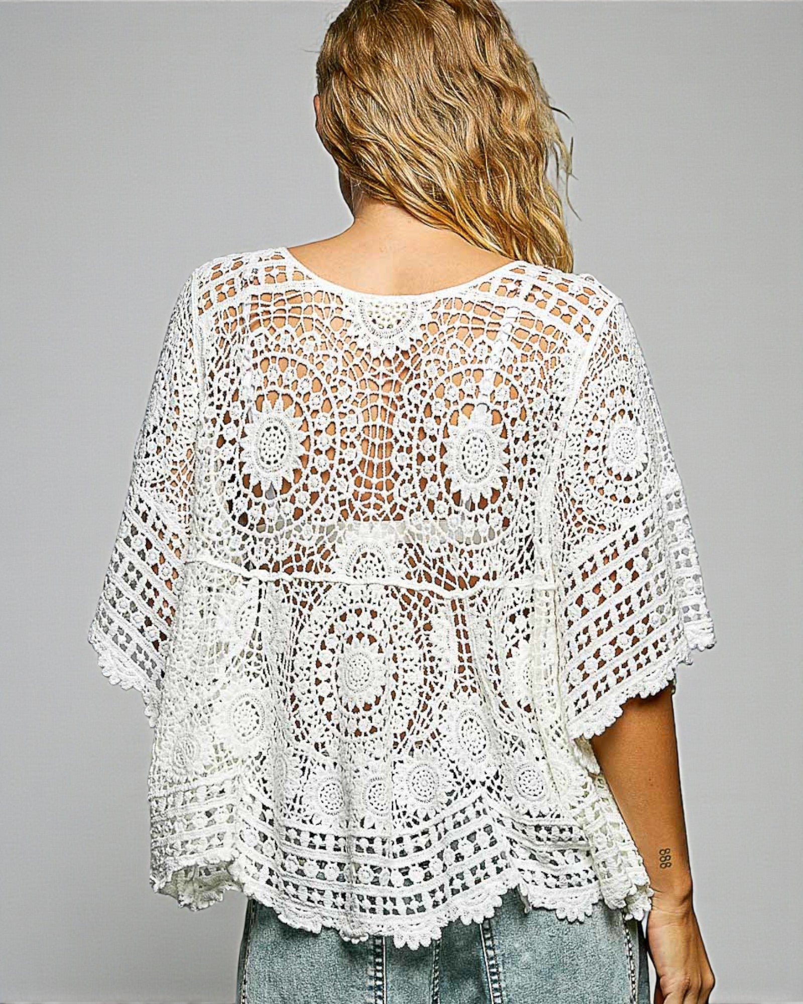 White crochet top worn by a person on a gray background