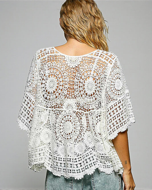 White crochet top worn by a person on a gray background