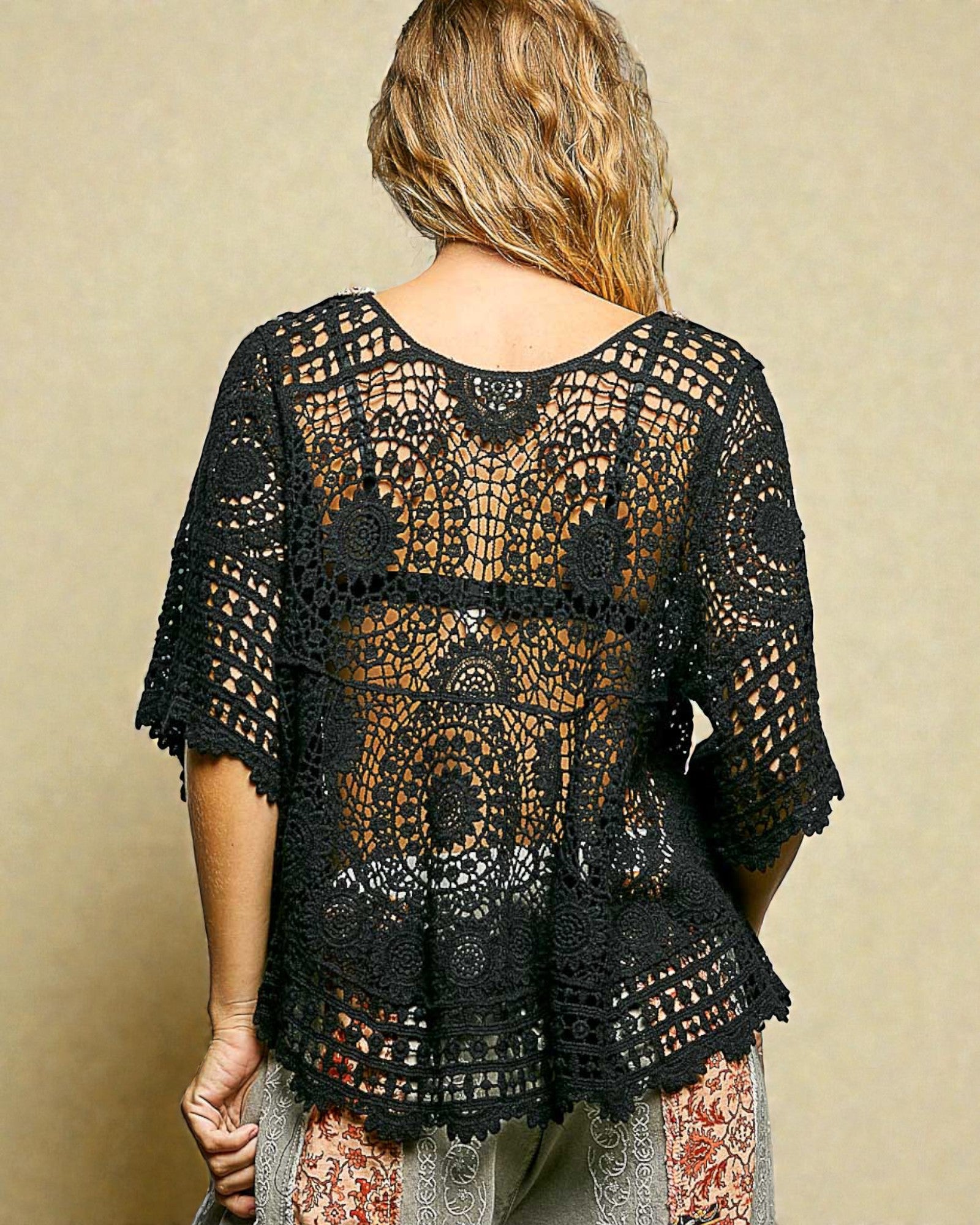 Black crochet top worn by a person on a beige background