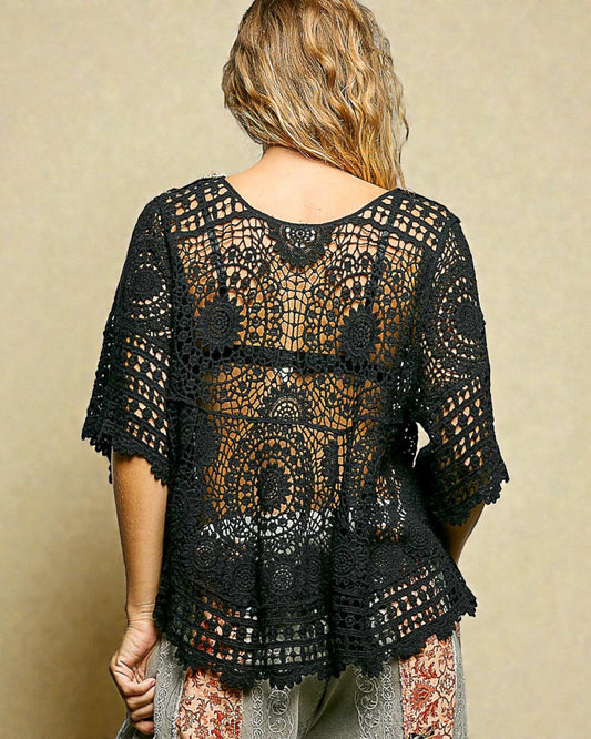 Black crochet top worn by a person on a beige background