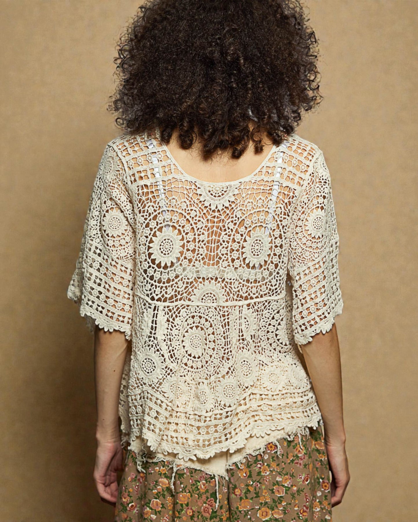 Person wearing a crochet top with a brown background