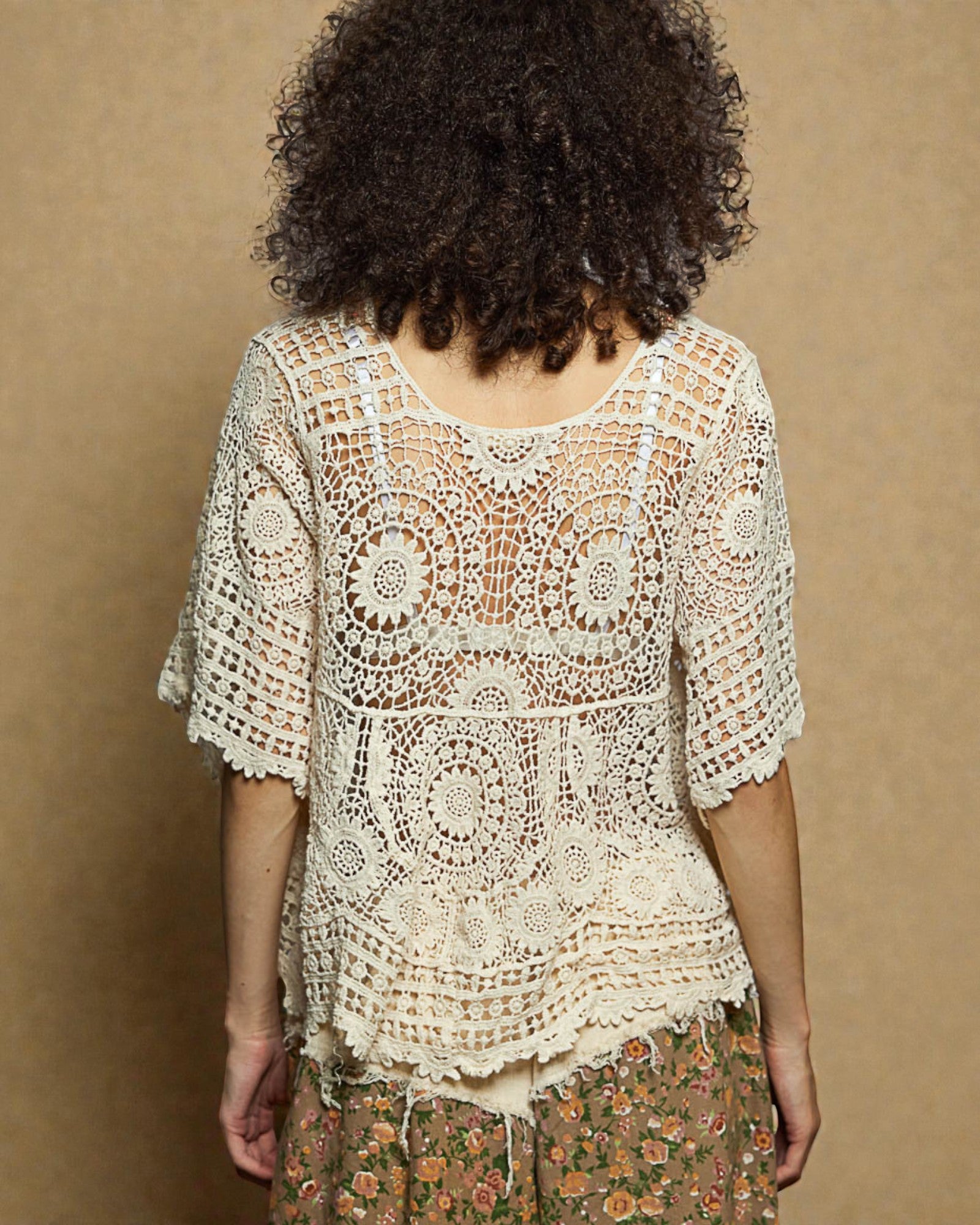Person wearing a crochet top with a brown background
