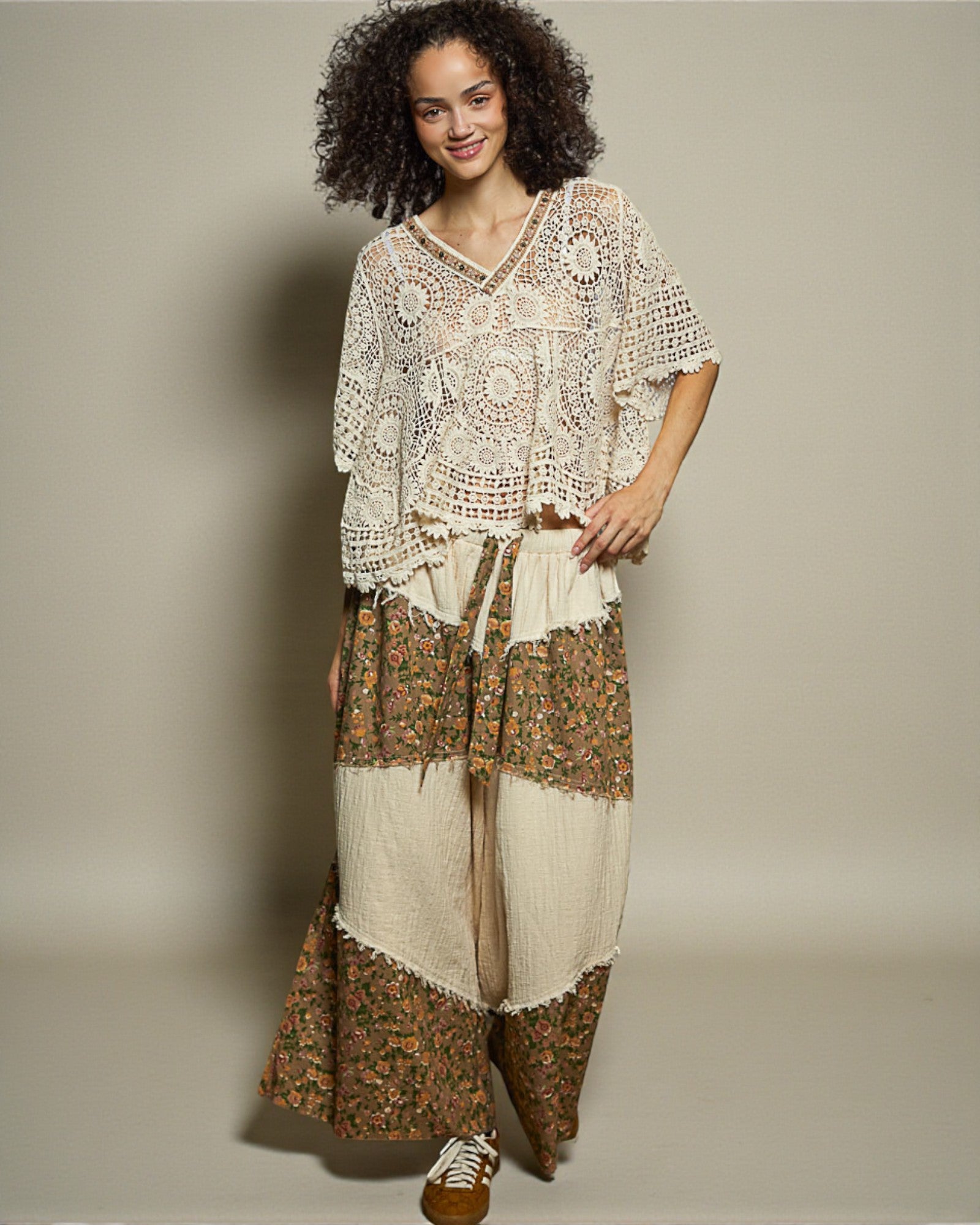 Woman wearing a bohemian-style outfit with a patterned top and skirt on a plain background